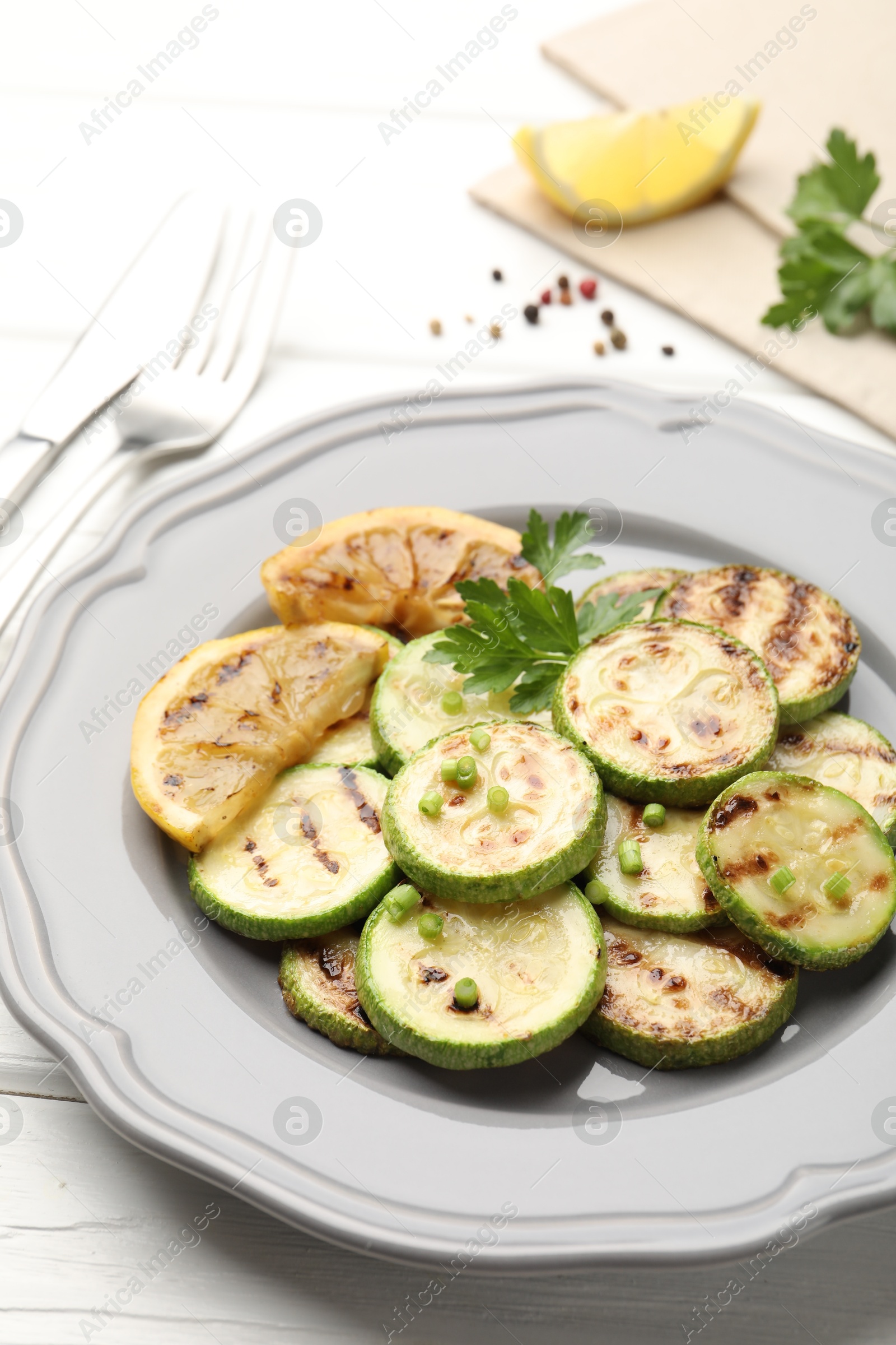 Delicious fried courgette slices with lemon and parsley served on white wooden table, closeup Photo of Delicious fried courgette slices with lemon and parsley served on white wooden table, closeup
