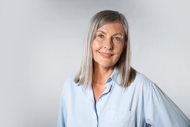 Photo of Portrait of beautiful senior woman on light background. Space for text