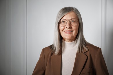 Photo of Portrait of beautiful senior woman near white wall. Space for text