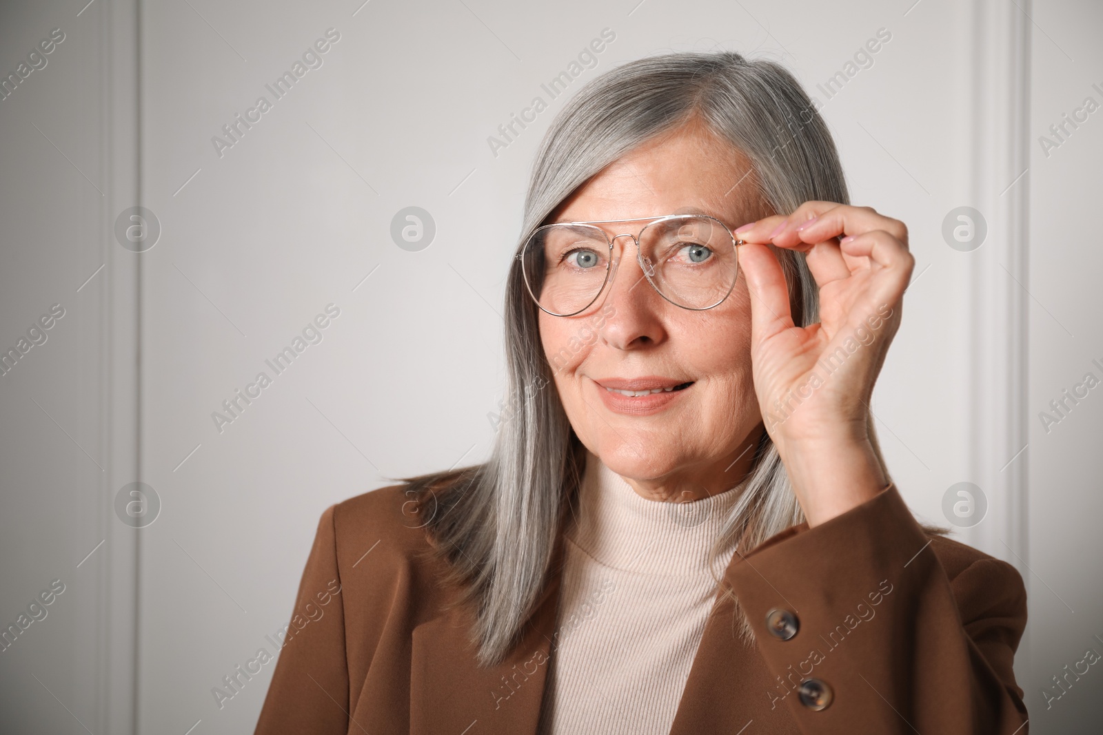 Photo of Portrait of beautiful senior woman near white wall. Space for text