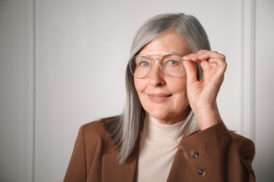 Photo of Portrait of beautiful senior woman near white wall. Space for text