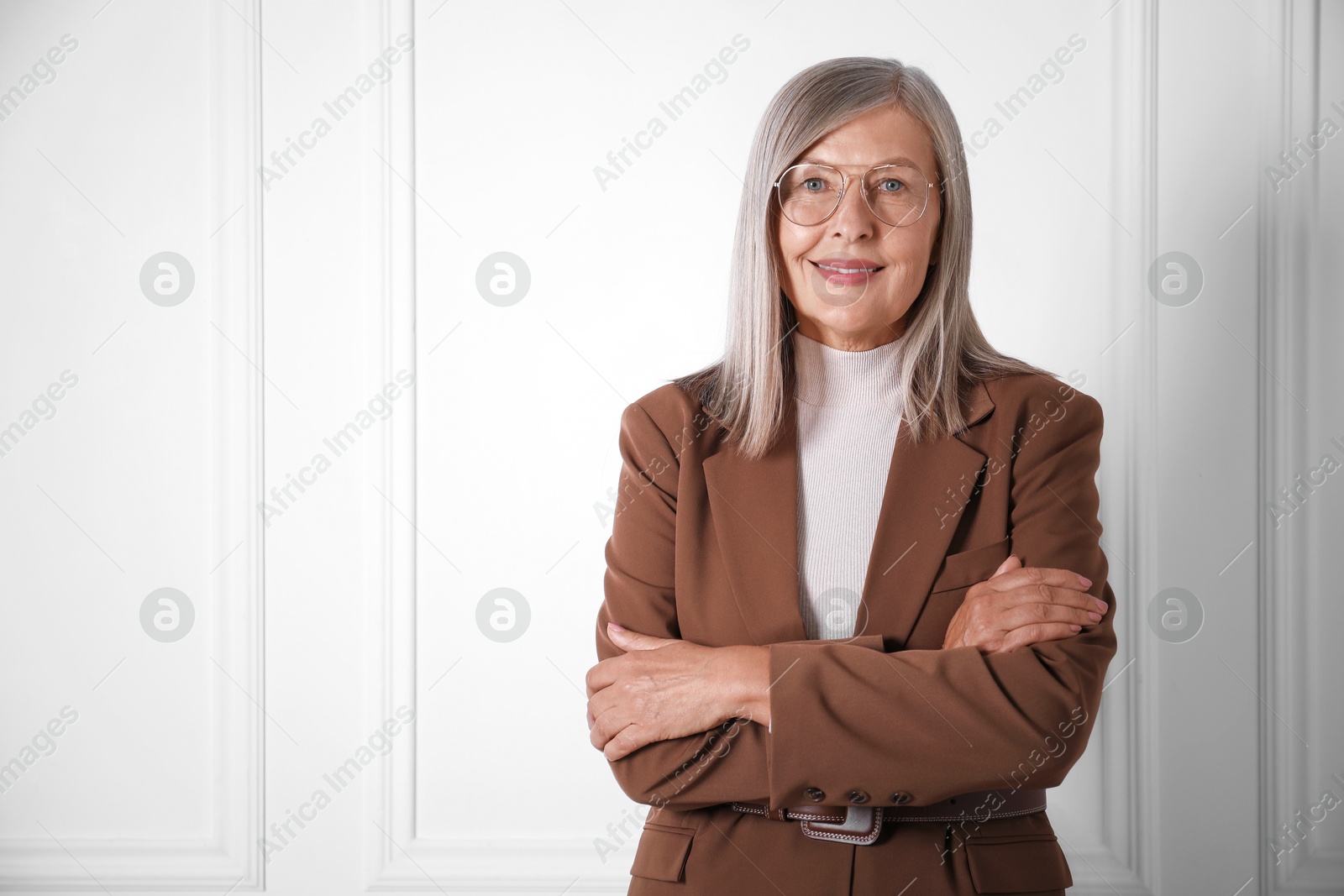 Photo of Portrait of beautiful senior woman near white wall. Space for text