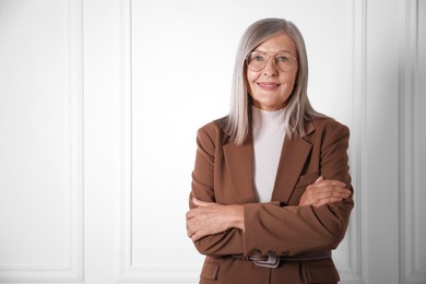 Photo of Portrait of beautiful senior woman near white wall. Space for text