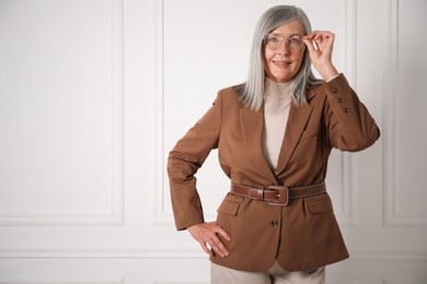 Photo of Portrait of beautiful senior woman near white wall. Space for text