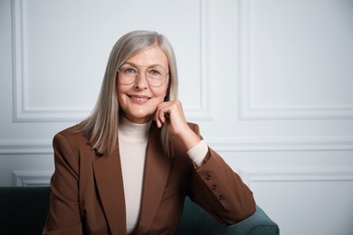 Photo of Portrait of beautiful senior woman on sofa near white wall. Space for text