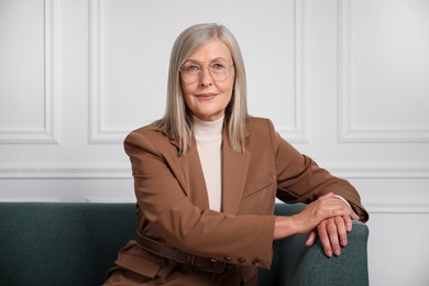 Photo of Portrait of beautiful senior woman on sofa near white wall