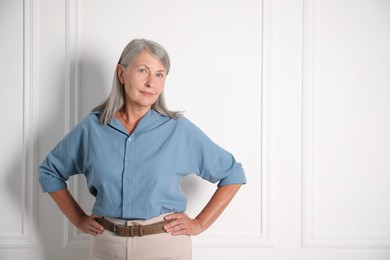 Photo of Portrait of beautiful senior woman near white wall. Space for text