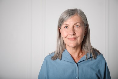 Photo of Portrait of beautiful senior woman near white wall. Space for text