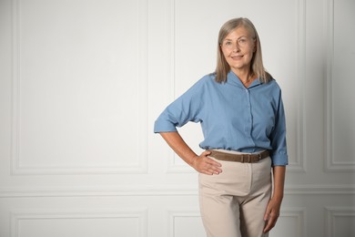Photo of Portrait of beautiful senior woman near white wall. Space for text