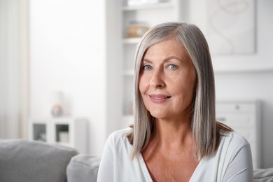 Photo of Elegant senior woman on sofa at home. Space for text