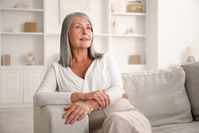 Photo of Elegant senior woman on sofa at home. Space for text