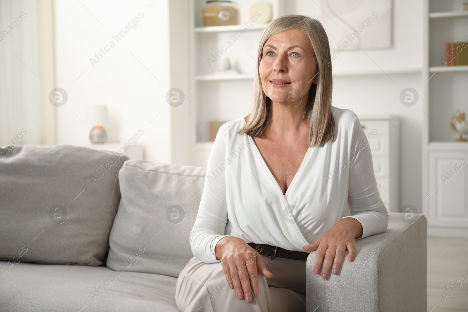 Photo of Elegant senior woman on sofa at home. Space for text