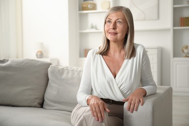 Photo of Elegant senior woman on sofa at home. Space for text
