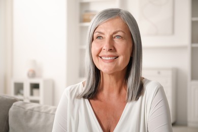 Photo of Elegant senior woman on sofa at home. Space for text