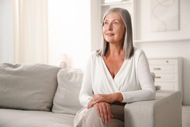 Photo of Elegant senior woman on sofa at home. Space for text