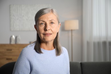 Photo of Elegant senior woman on sofa at home. Space for text