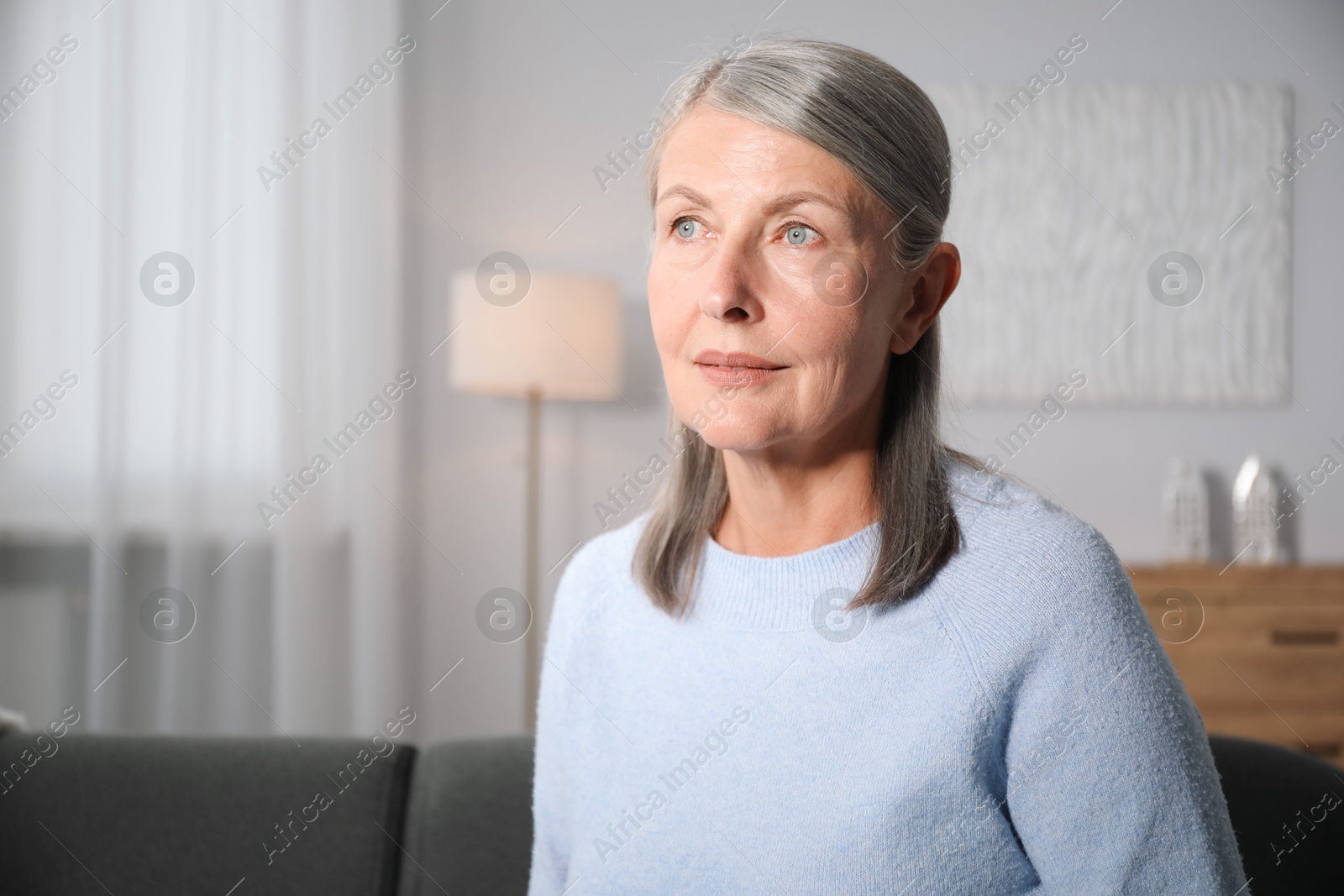 Photo of Elegant senior woman on sofa at home. Space for text
