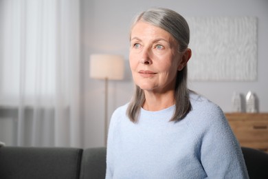 Photo of Elegant senior woman on sofa at home. Space for text