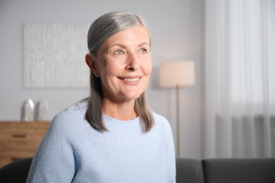 Photo of Elegant senior woman on sofa at home. Space for text