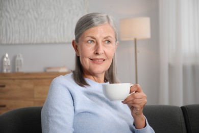 Photo of Senior woman having tea on sofa at home