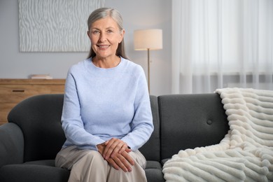 Photo of Elegant senior woman on sofa at home. Space for text
