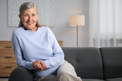 Photo of Elegant senior woman on sofa at home. Space for text