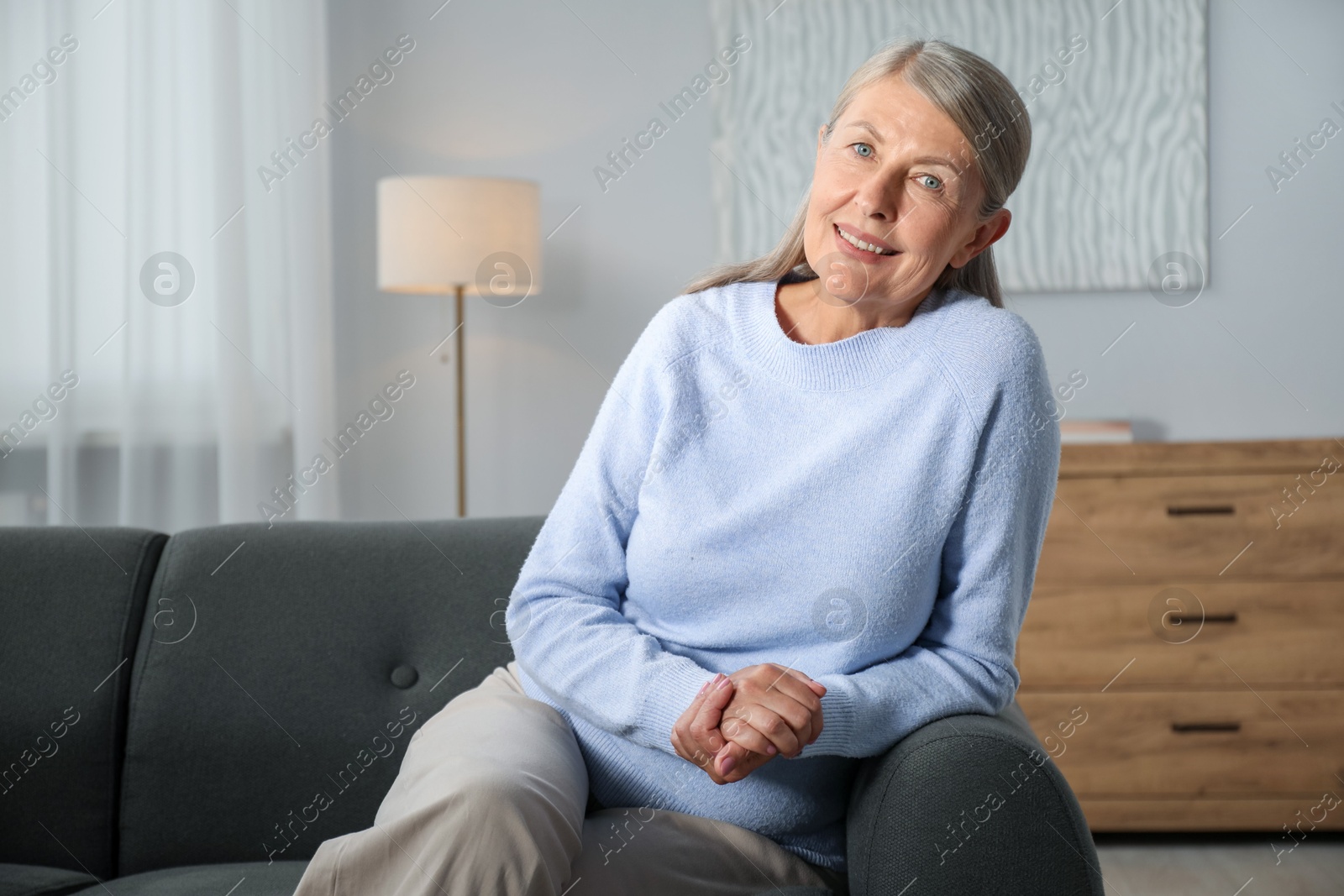Photo of Elegant senior woman on sofa at home. Space for text