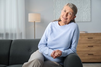 Photo of Elegant senior woman on sofa at home. Space for text