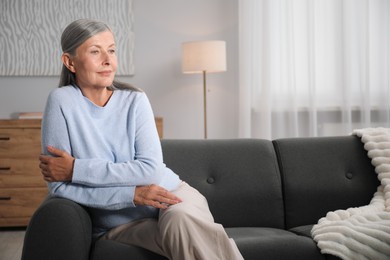Photo of Elegant senior woman on sofa at home. Space for text