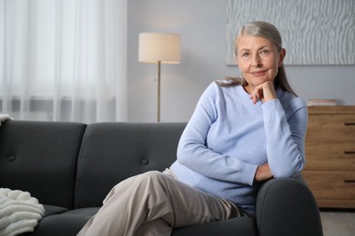 Photo of Elegant senior woman on sofa at home. Space for text
