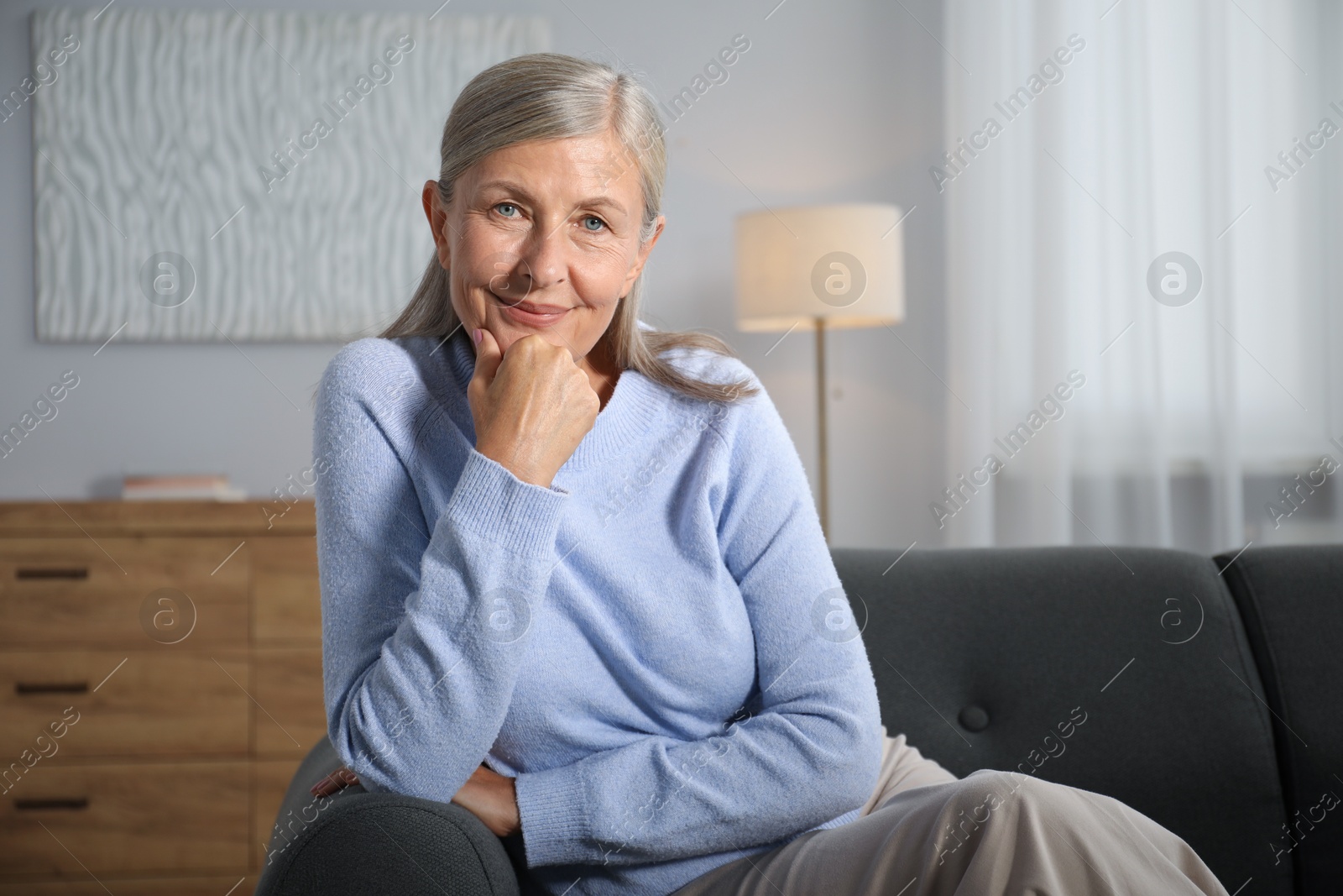 Photo of Elegant senior woman on sofa at home. Space for text