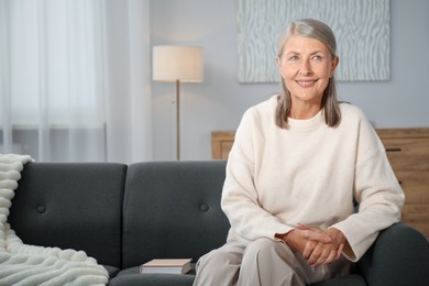 Photo of Elegant senior woman on sofa at home. Space for text