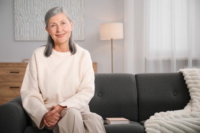 Photo of Elegant senior woman on sofa at home. Space for text