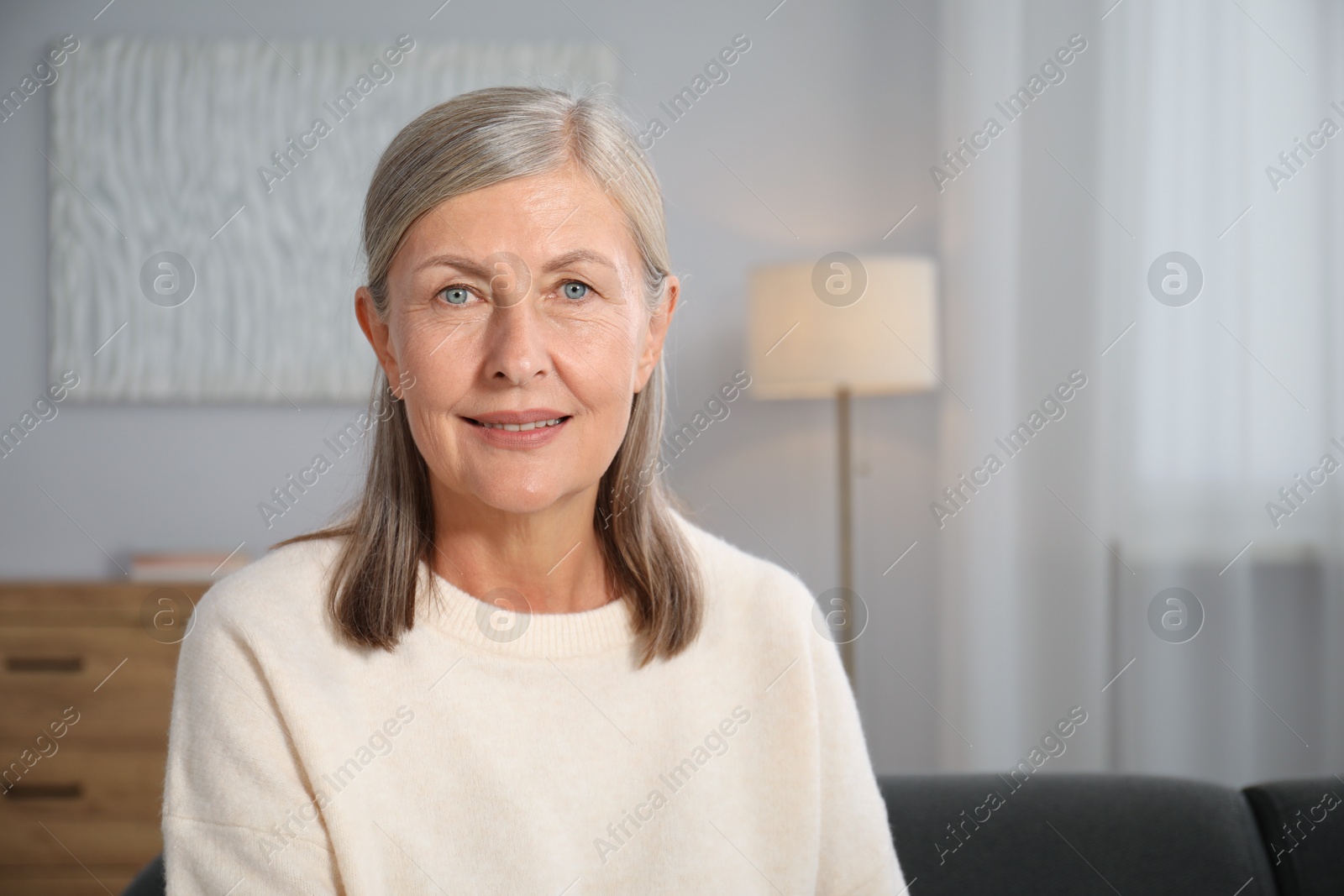 Photo of Elegant senior woman on sofa at home. Space for text