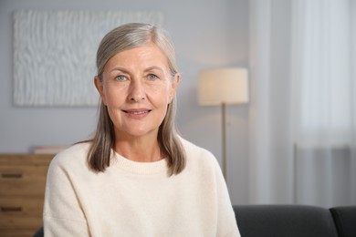 Photo of Elegant senior woman on sofa at home. Space for text