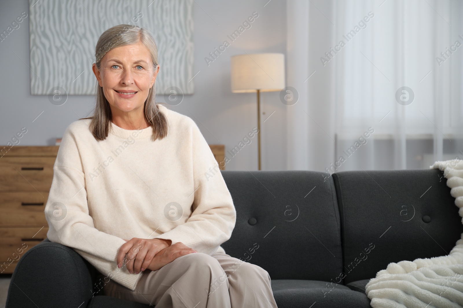Photo of Elegant senior woman on sofa at home. Space for text