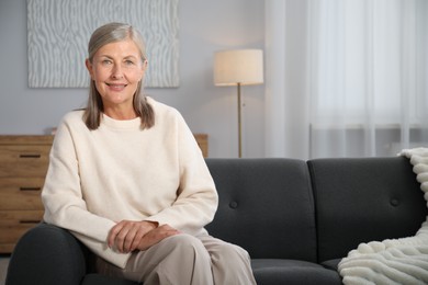 Photo of Elegant senior woman on sofa at home. Space for text