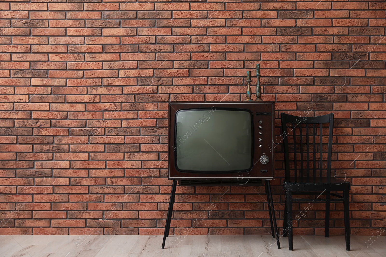 Retro TV on stand and black chair near red brick wall, space for text. Used stuff Photo of Retro TV on stand and black chair near red brick wall, space for text. Used stuff
