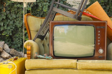 Photo of Retro TV on sofa and other used stuff outdoors