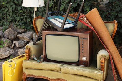 Photo of Retro TV on sofa and other used stuff outdoors