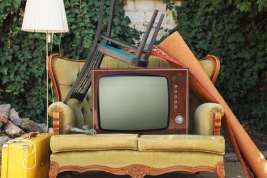 Photo of Retro TV on sofa and other used stuff outdoors