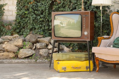 Photo of Retro TV on stand, suitcases and other used stuff outdoors