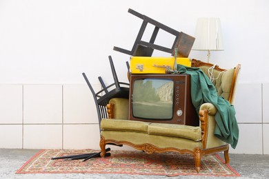 Photo of Retro TV on sofa and other used stuff near white wall outdoors