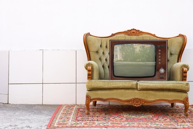 Photo of Retro TV on sofa and carpet near white wall outdoors, space for text. Used stuff