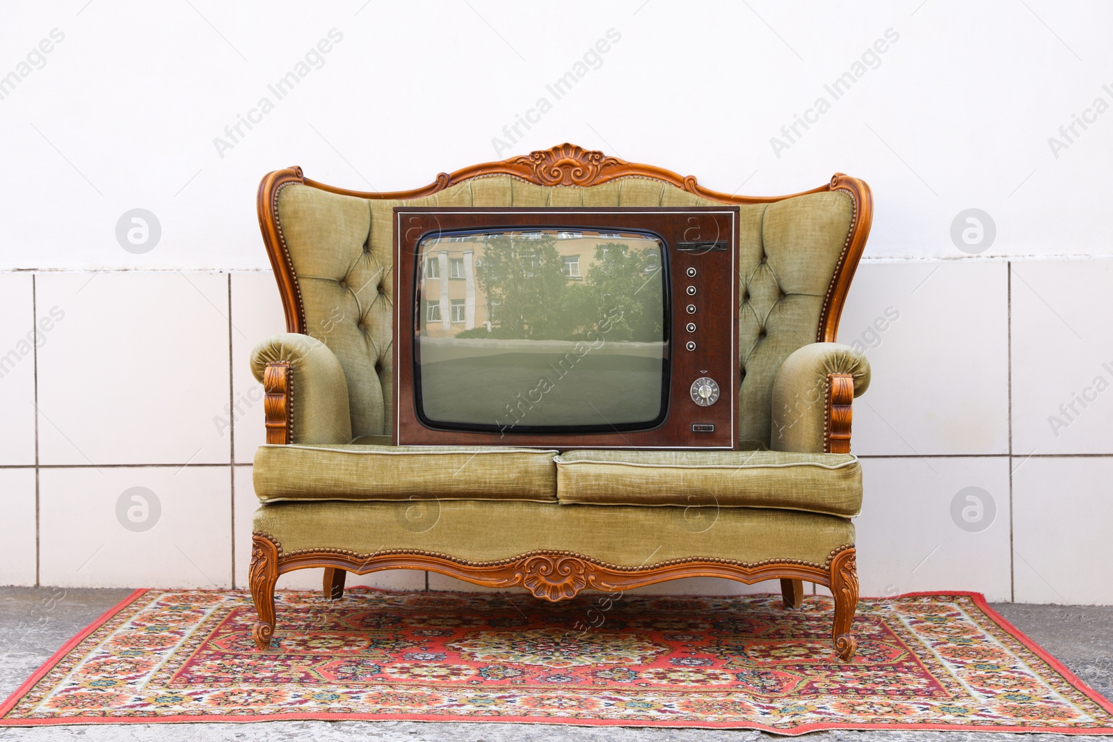 Retro TV on sofa and carpet near white wall outdoors. Used stuff Photo of Retro TV on sofa and carpet near white wall outdoors. Used stuff