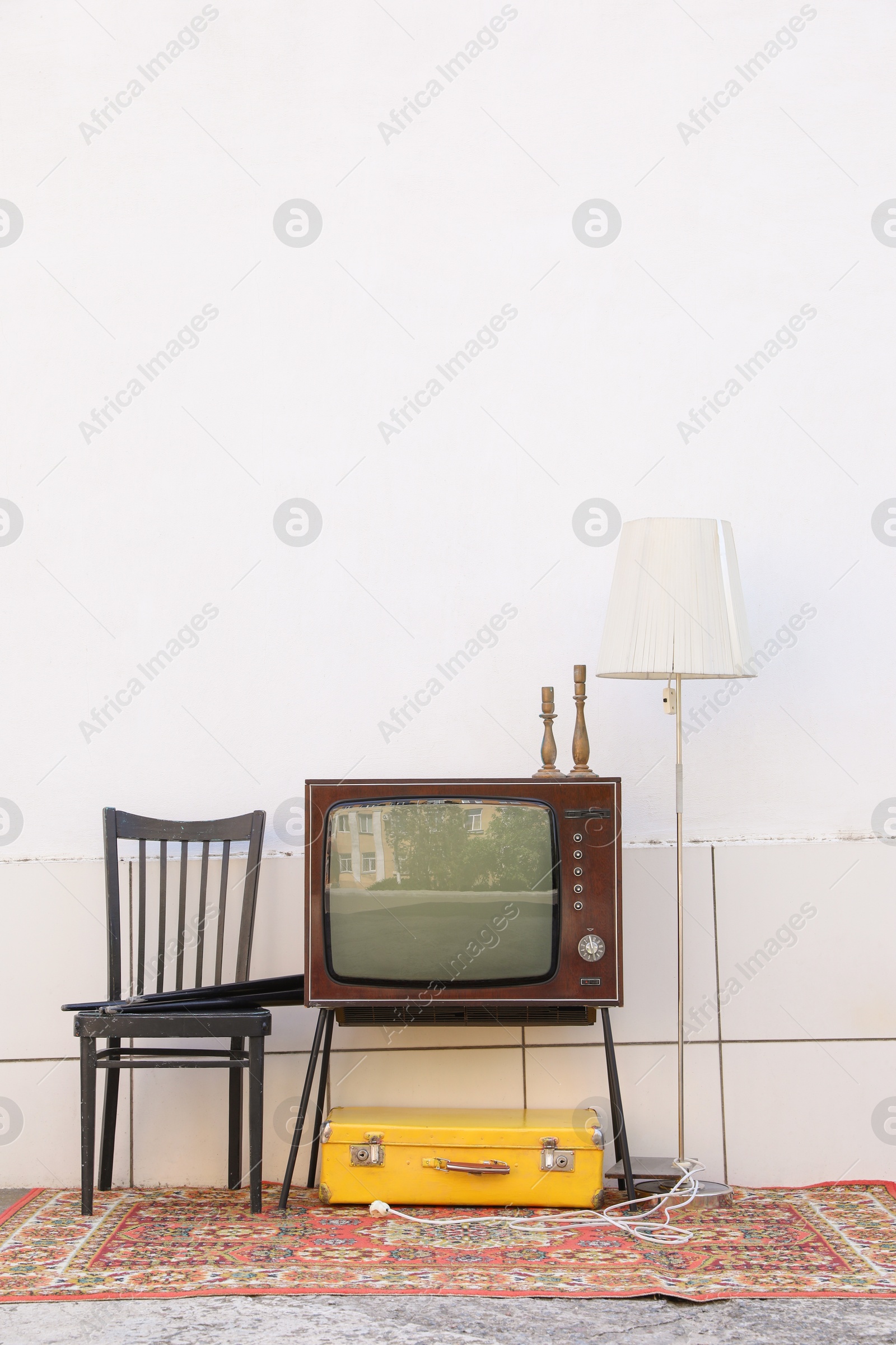 Retro TV on stand and other used stuff near white wall outdoors Photo of Retro TV on stand and other used stuff near white wall outdoors