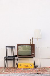Photo of Retro TV on stand and other used stuff near white wall outdoors