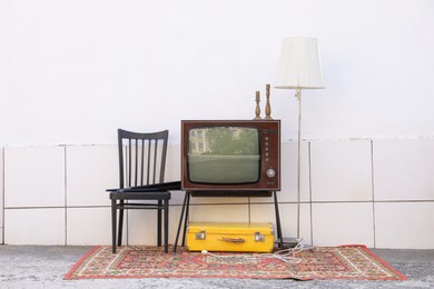Photo of Retro TV on stand and other used stuff near white wall outdoors