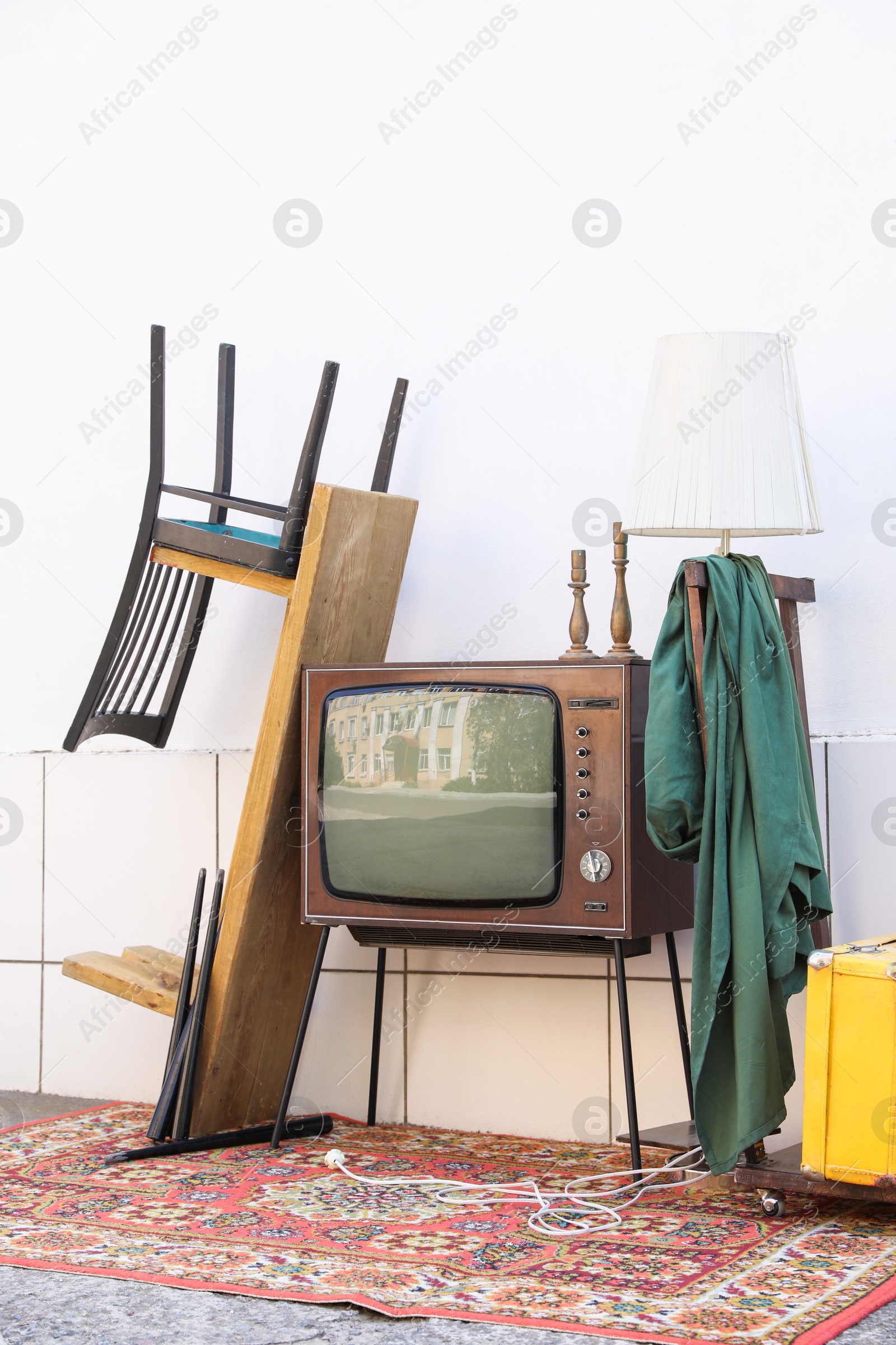 Retro TV on stand and other used stuff near white wall outdoors Photo of Retro TV on stand and other used stuff near white wall outdoors