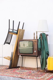 Photo of Retro TV on stand and other used stuff near white wall outdoors